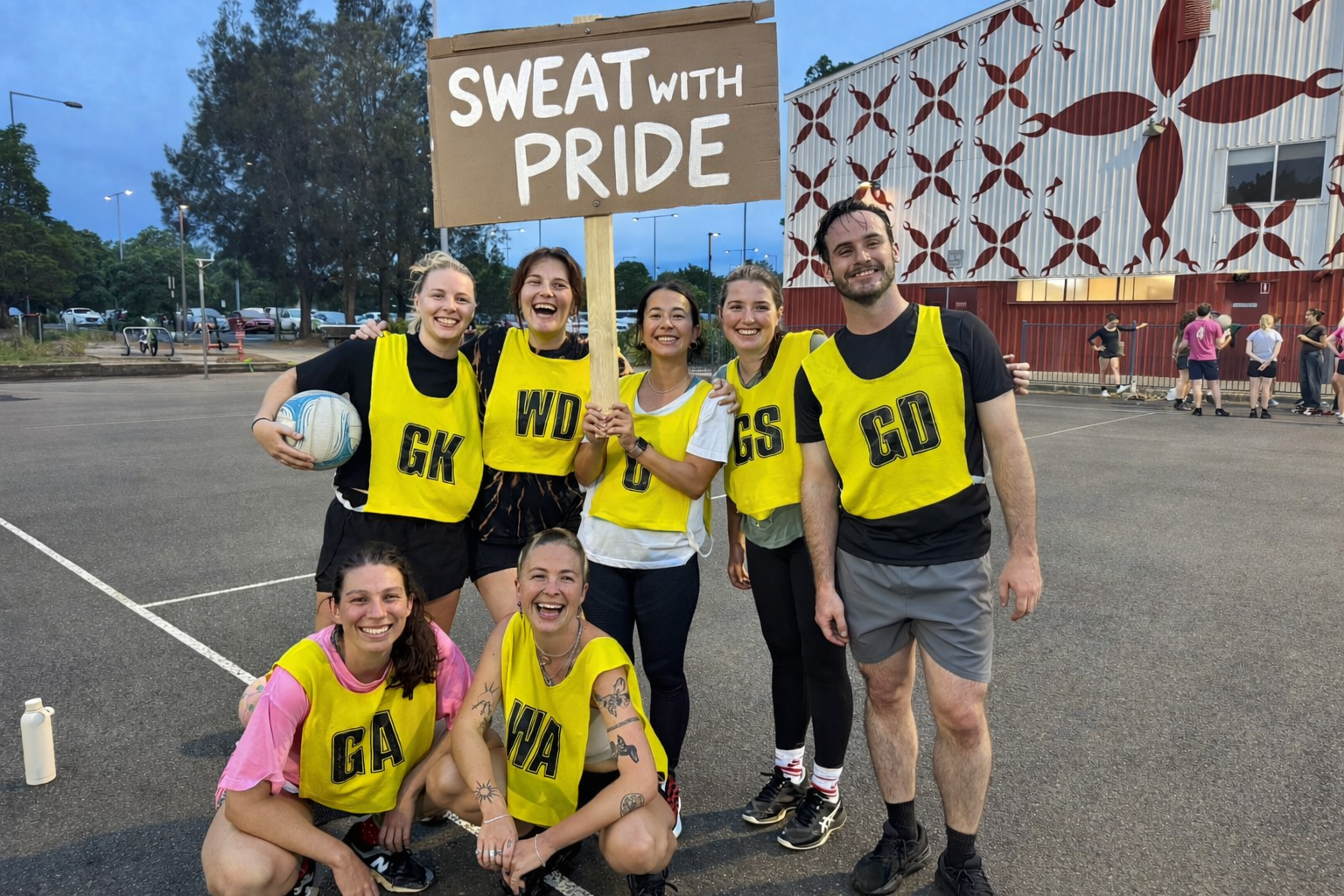 People playing netball with a sweat with pride sign