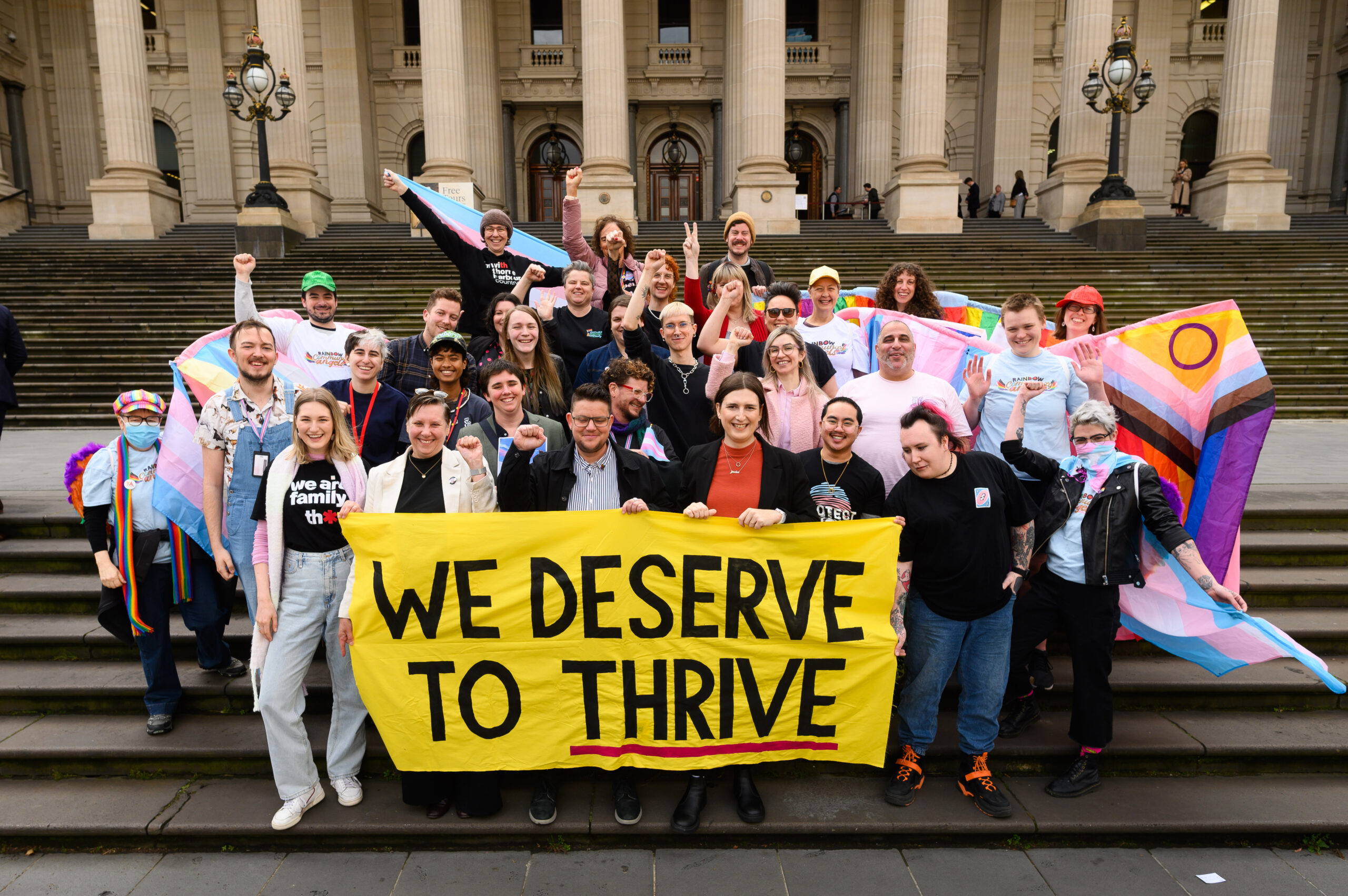 Group of people with the sign 'we deserve to thrive'