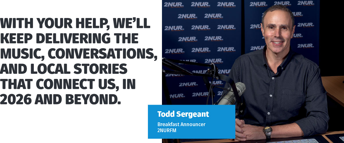 A radio host sitting behind the desk smiling to camera.