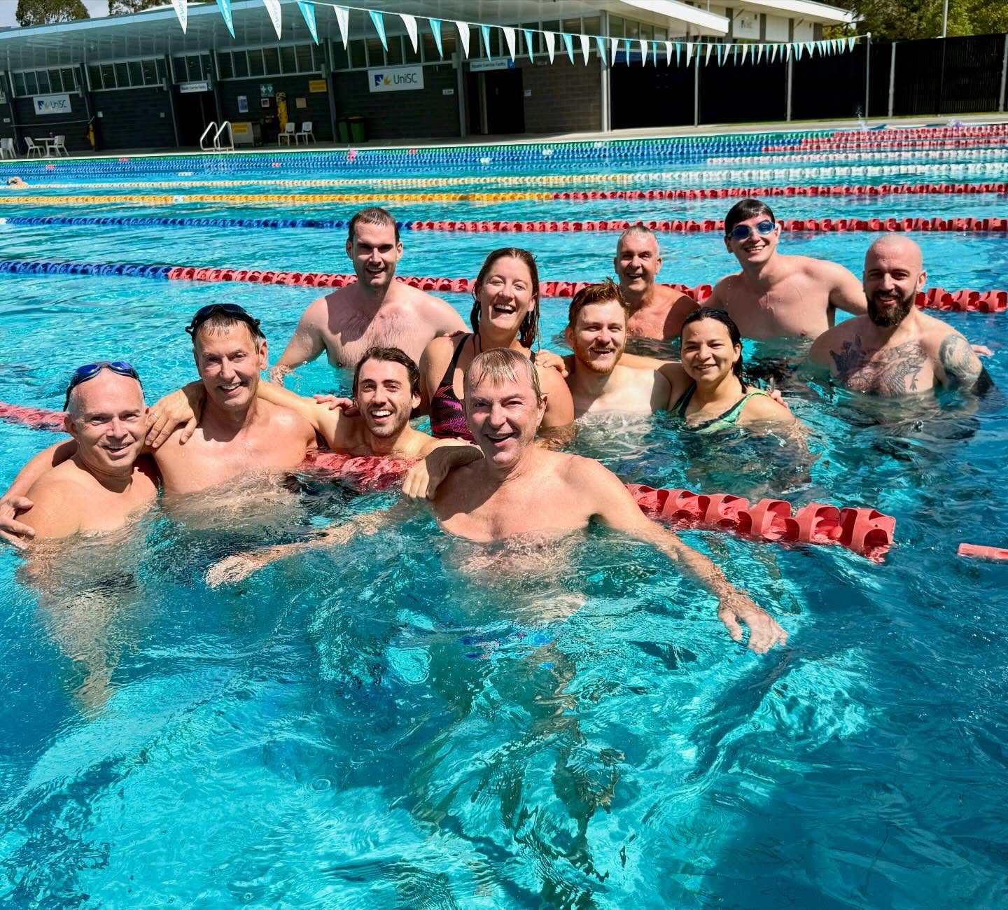 Water polo team in a pool smiling at the camers