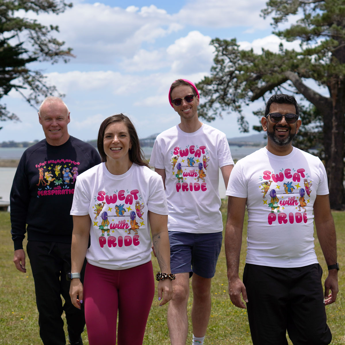 Photo of four people walking in a park. They are all wearing Sweat with Pride t-shirts.